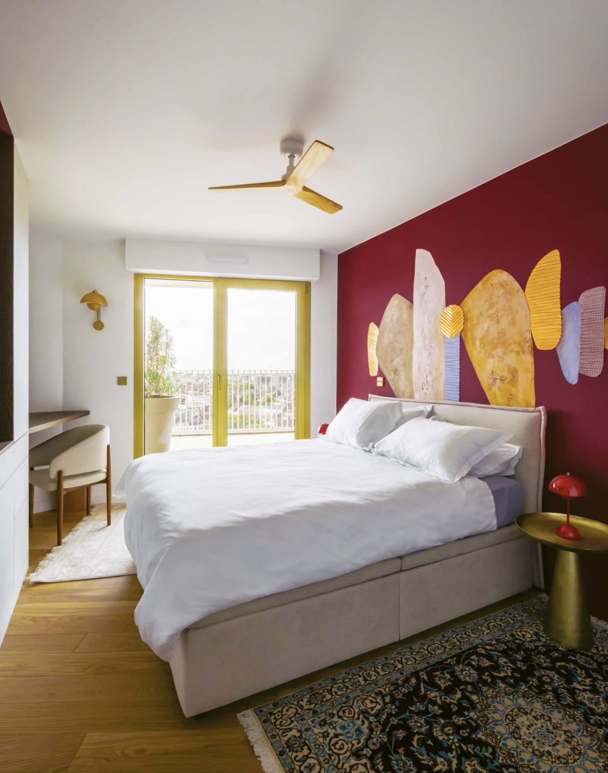 Chambre sur-mesure avec fresque d'Elsa Jeandedieu sur fond bordeaux profond, créant un dialogue esthétique avec le reste de l'appartement