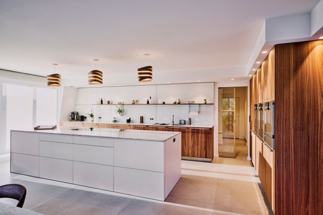 Cuisine ouverture avec ilôt central et meubles en noyer d'un appartement aménagé sur plan en VEFA